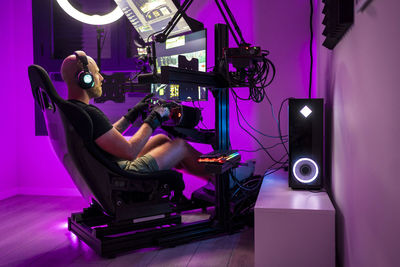 Man playing video game while sitting on chair at studio