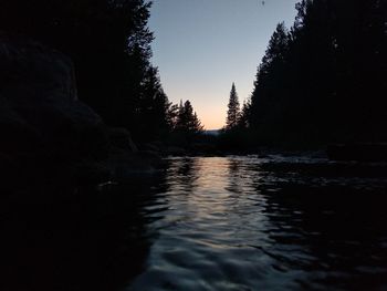 River amidst silhouette trees against clear sky