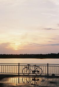 Silhouette pier over lake against sky during sunset