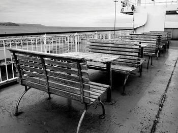 Empty benches in row against sky