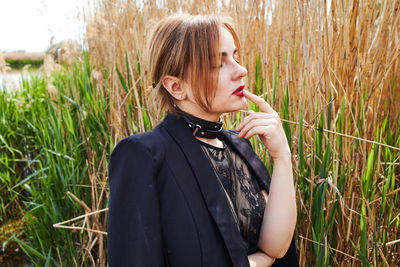 Portrait of young woman standing against plants