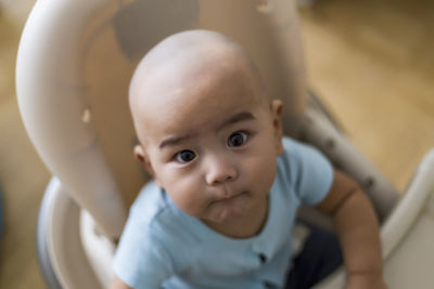 Portrait of cute baby sitting in high chair at home