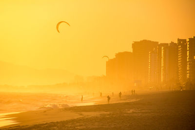 People by sea against sky during sunset