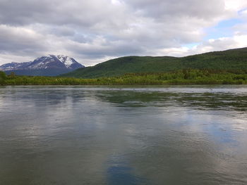 Scenic view of lake by mountains against sky