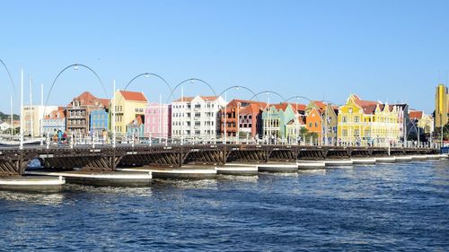 Queen emma pontoon bridge over sea by cityscape against sky