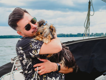 Handsome man hugging and kissing his small dog yorkshire terrier