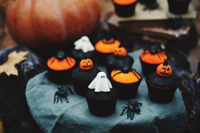 Close-up of cupcakes and pumpkin on table during halloween celebration