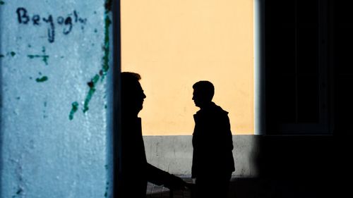Silhouette man standing by window of building