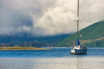 Boat in sea against cloudy sky