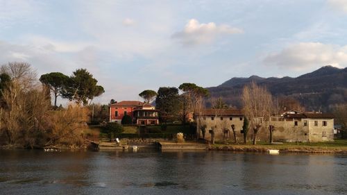 Houses by lake and buildings against sky