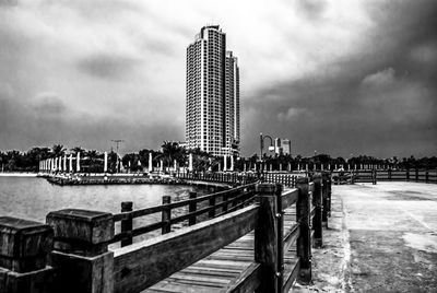 Bridge over river by buildings against sky