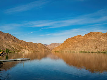 Scenic view of lake and mountains against blue sky