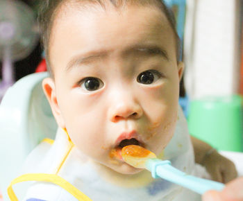 Close-up portrait of cute boy with hand feeding