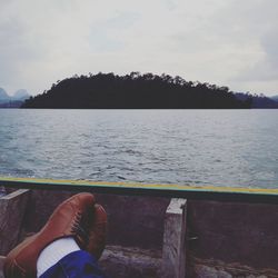 Low section of man on lake against sky