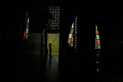 Rear view of silhouette man walking in illuminated building at night