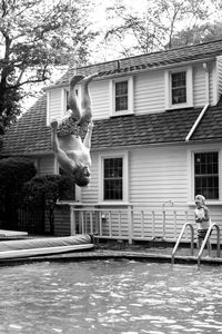 Man jumping in swimming pool against house