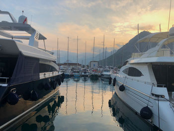 Boats moored in harbor at sunset