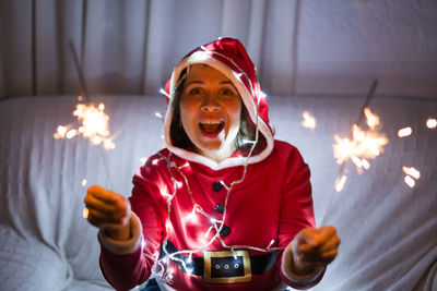 Young woman holding illuminated christmas lights at home