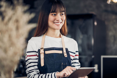 Smiling barista using digital tablet in cafe