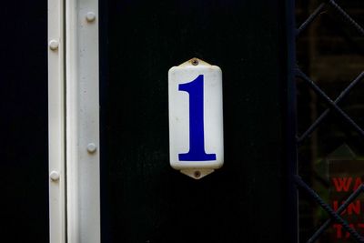 Close-up of sign on blue door number 1
