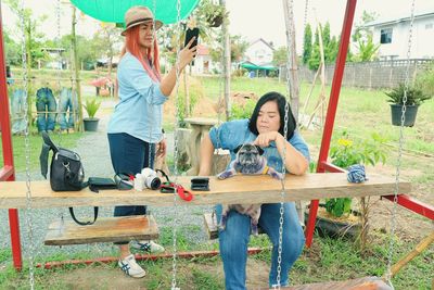 Woman photographing while standing by swing 