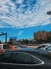 Cars on road by buildings against sky