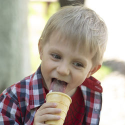 Cute boy licking ice cream in garden