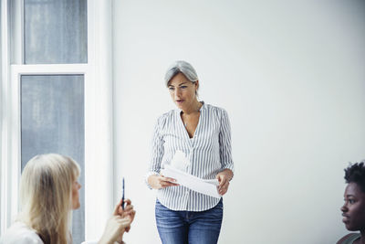 Mature businesswoman discussing with colleagues in creative office