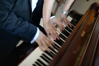 Midsection of hands playing piano