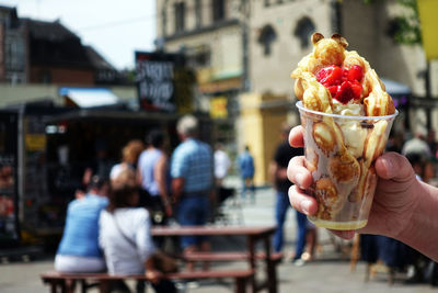 Hand holding ice cream cone in city