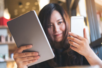 Smiling woman using digital tablet while sitting in cafe