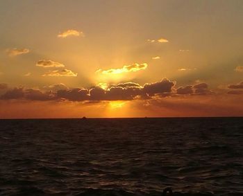 Scenic view of sea against dramatic sky during sunset