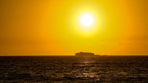 Silhouette of a big ship moving at the horizon during a beautiful summer sunset. ferry boat navigate