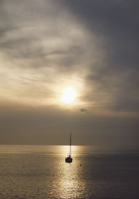 Silhouette sailboat sailing on sea against sky during sunset