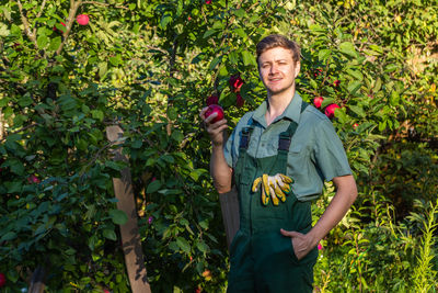 Portrait of young woman standing against plants