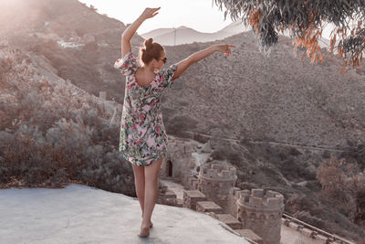 Full length of woman with arms raised standing in park