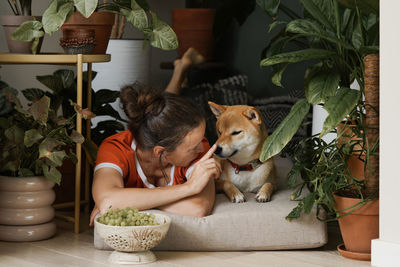 Adult woman resting at home with her best furry friend ginger dog in floral nook. biophillia design