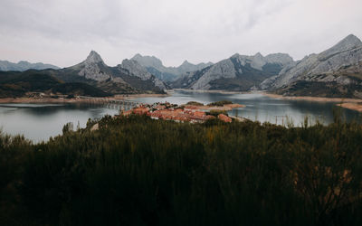 Scenic view of lake and mountains with village in the middle