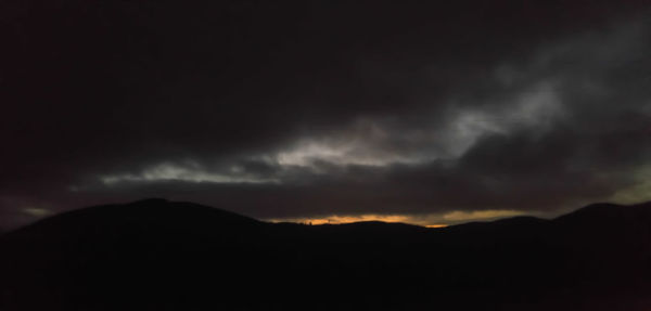 Silhouette of mountain range against dramatic sky