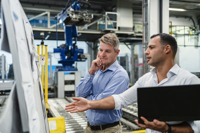 Male mature colleagues in meeting discussing while standing in industry
