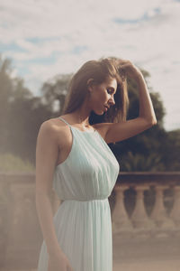 Young woman standing against sky