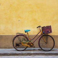 Bicycle parked against yellow wall