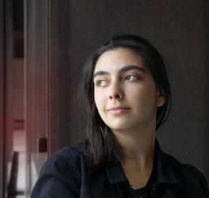 Thoughtful teenage girl against wall at home