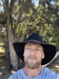 Portrait of man wearing hat against trees