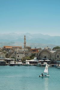Boats in sea against buildings in city