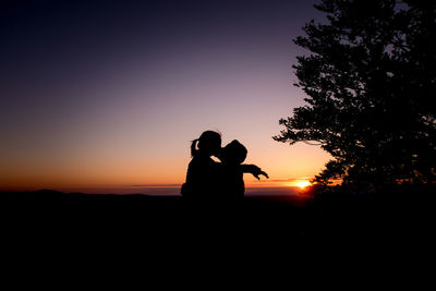 Silhouette couple against orange sky during sunset