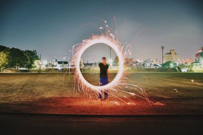 Rear view of woman standing in park against sky at night