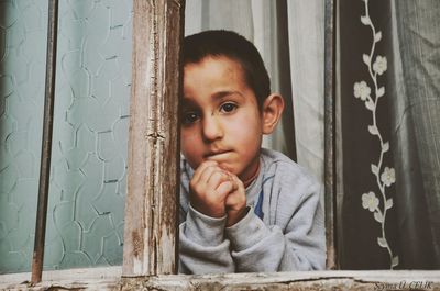 Cute baby boy looking through window