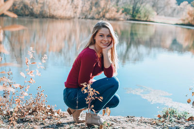 Portrait of smiling young woman against lake