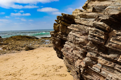 Rock formations on beach against sky